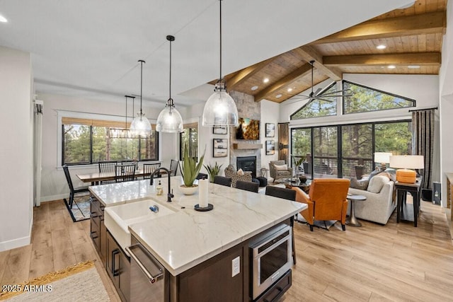 kitchen featuring a sink, a fireplace, stainless steel appliances, open floor plan, and beamed ceiling