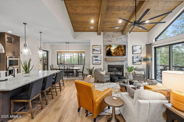 living area with wooden ceiling, plenty of natural light, light wood finished floors, and a stone fireplace