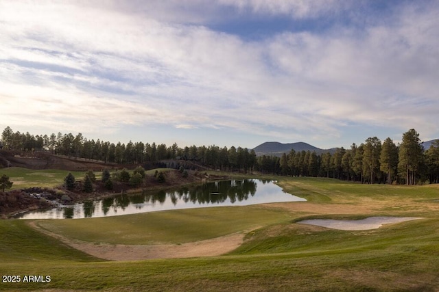 view of home's community with a water and mountain view, a lawn, and golf course view