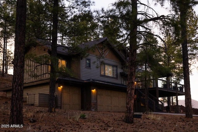 exterior space featuring stairs, an attached garage, and a deck