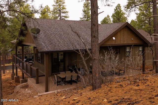 rear view of house featuring a patio and a shingled roof