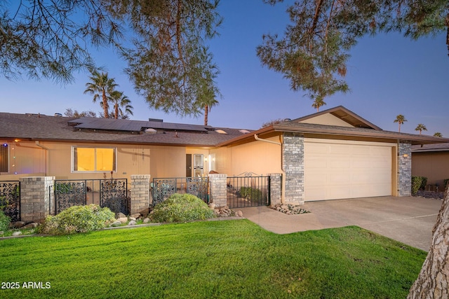 ranch-style house featuring a yard, a garage, and solar panels