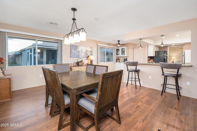 dining room with hardwood / wood-style flooring, ceiling fan, and a textured ceiling