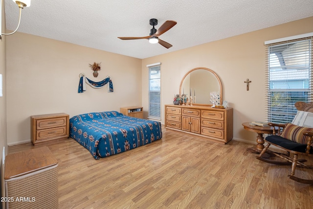 bedroom with a textured ceiling, light hardwood / wood-style floors, and ceiling fan