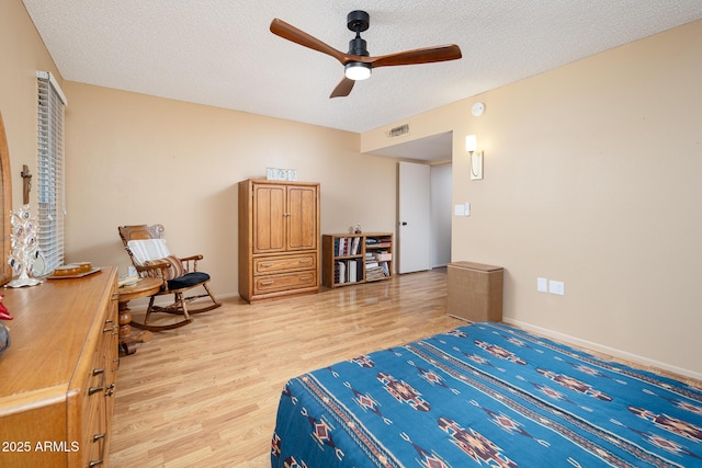 bedroom featuring ceiling fan, light hardwood / wood-style flooring, and a textured ceiling