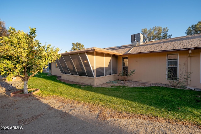 view of side of home with a sunroom, a yard, and cooling unit