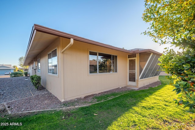 view of property exterior with a lawn and a sunroom