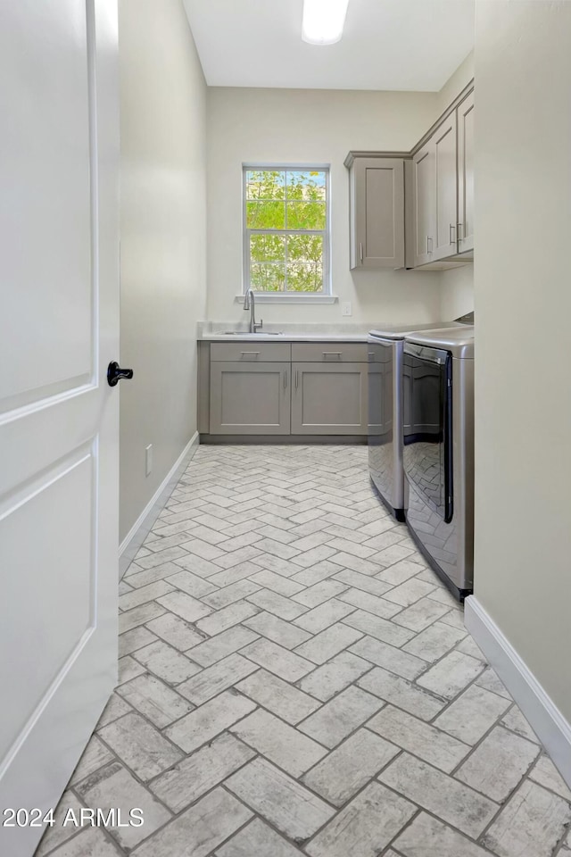 laundry room with washer and clothes dryer, cabinets, and sink