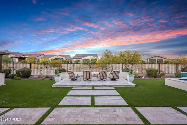 patio terrace at dusk featuring a yard