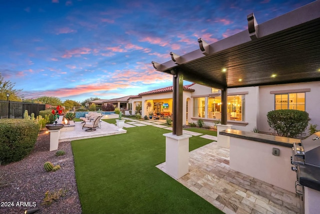 yard at dusk with an outdoor kitchen, a patio area, and a swimming pool