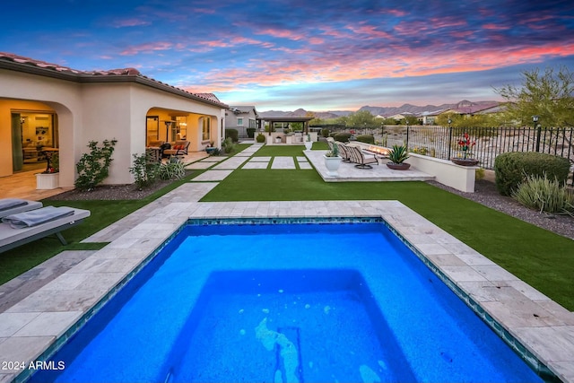 pool at dusk with a patio area and a hot tub