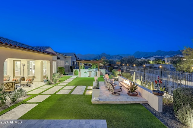 view of yard with a mountain view, an outdoor living space with a fire pit, and a patio area