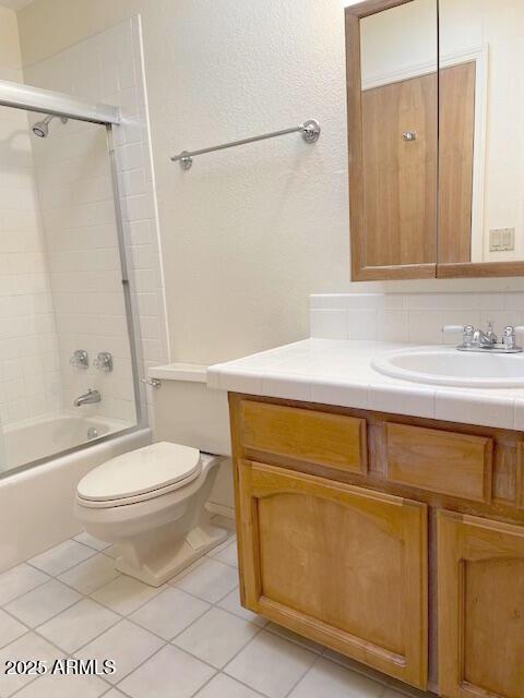 full bathroom featuring combined bath / shower with glass door, tasteful backsplash, vanity, tile patterned flooring, and toilet