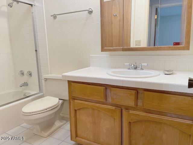 full bathroom with tile patterned flooring, tiled shower / bath combo, toilet, and vanity