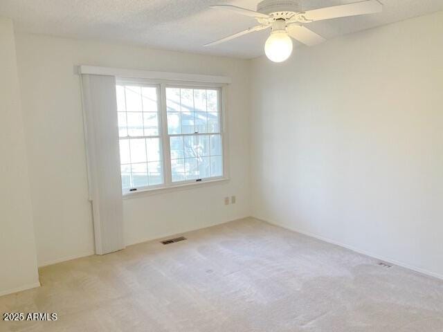 unfurnished room with ceiling fan, light colored carpet, and a textured ceiling