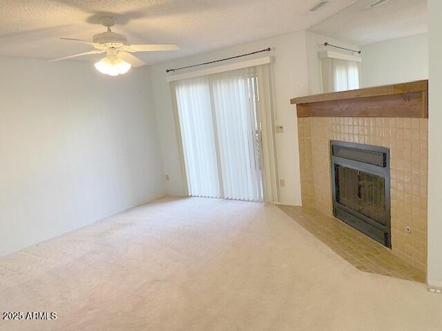 unfurnished living room featuring a fireplace, carpet, a textured ceiling, and ceiling fan