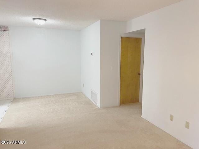 spare room with a textured ceiling and light colored carpet