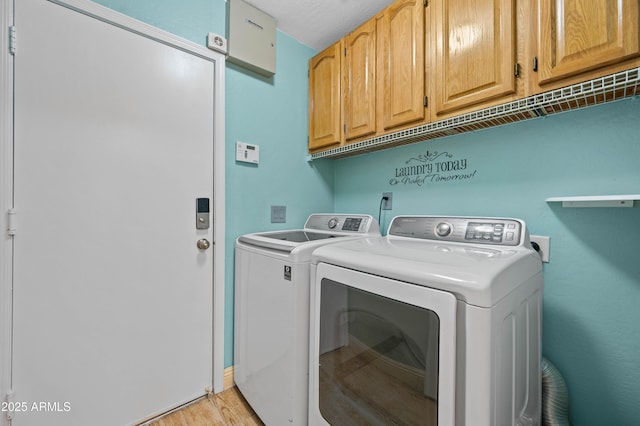 washroom with light wood-type flooring, cabinet space, and washer and dryer