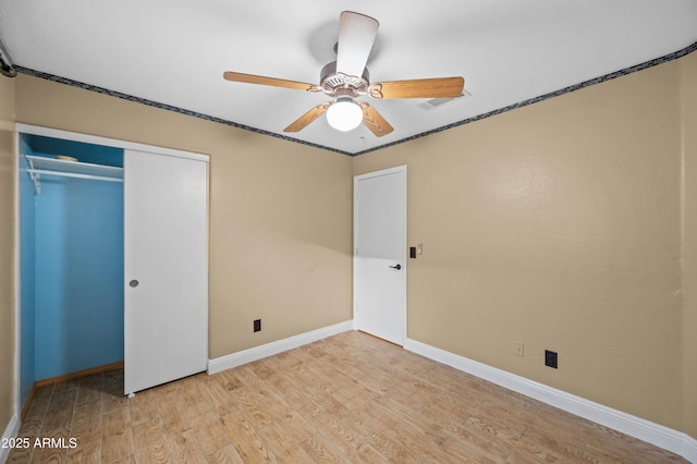 unfurnished bedroom featuring light wood finished floors, a ceiling fan, baseboards, and a closet