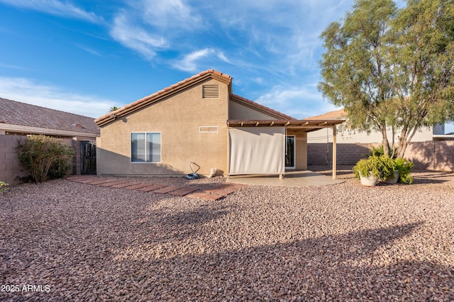 back of house with stucco siding, a tile roof, fence, and a patio