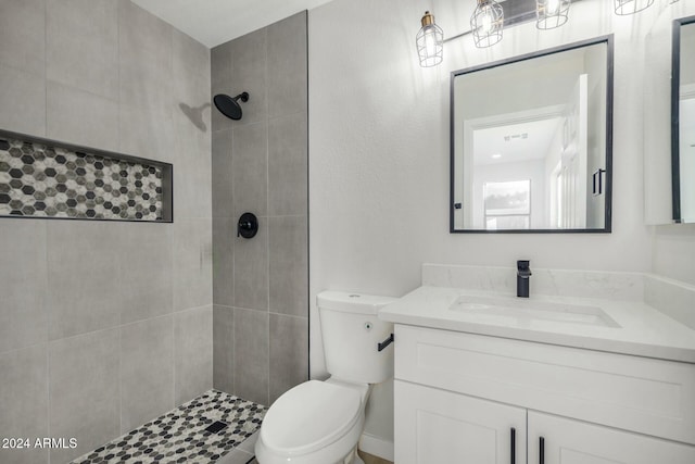 bathroom featuring tiled shower, vanity, and toilet