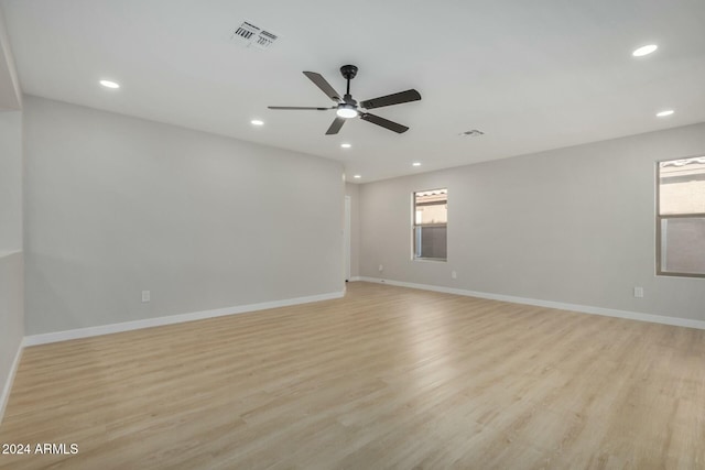 empty room featuring ceiling fan, plenty of natural light, and light wood-type flooring