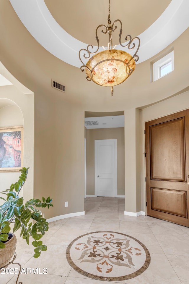 foyer entrance featuring light tile patterned floors, a towering ceiling, and an inviting chandelier