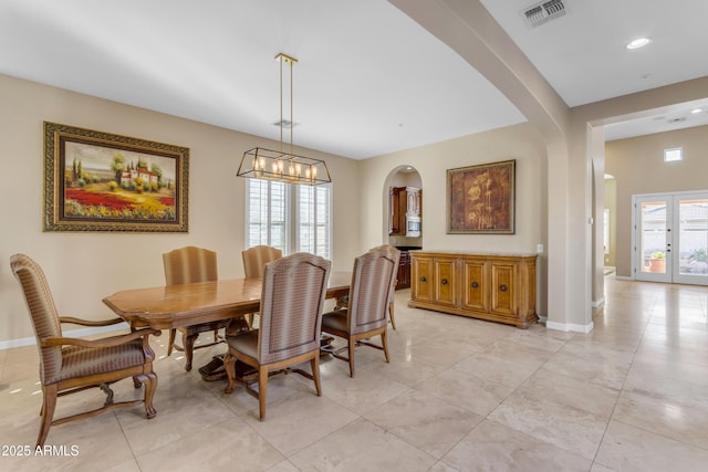 tiled dining room featuring a notable chandelier and french doors