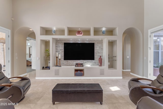 living room with built in features, a towering ceiling, and light tile patterned floors