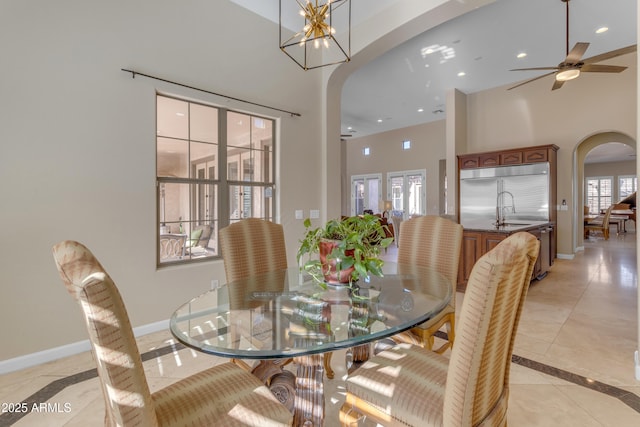 tiled dining area with sink and ceiling fan with notable chandelier