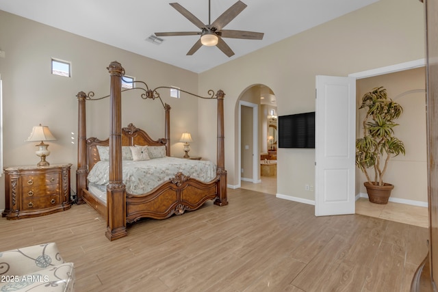 bedroom with ceiling fan, ensuite bathroom, and light wood-type flooring