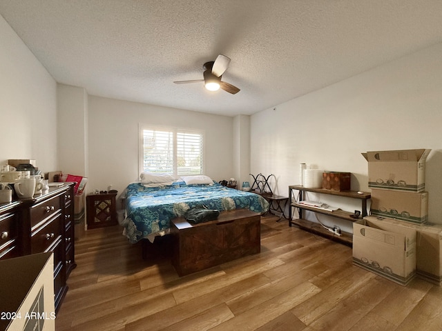 bedroom with hardwood / wood-style floors, a textured ceiling, and ceiling fan