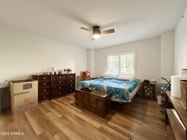 bedroom featuring ceiling fan, light hardwood / wood-style floors, and a textured ceiling