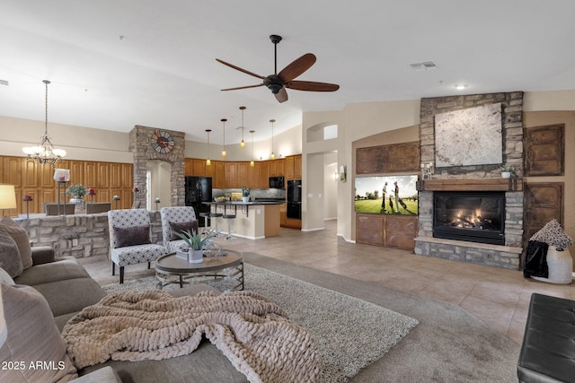 living room featuring light tile patterned flooring, high vaulted ceiling, ceiling fan with notable chandelier, and a fireplace