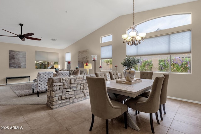 tiled dining room with ceiling fan with notable chandelier and high vaulted ceiling