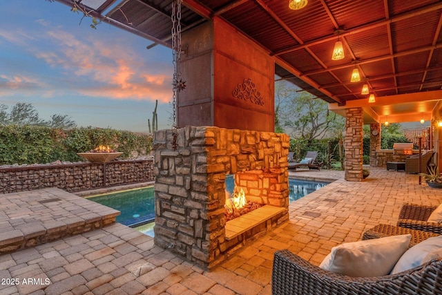 patio terrace at dusk featuring a fenced in pool and exterior kitchen