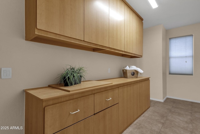 kitchen with light tile patterned floors, butcher block countertops, and light brown cabinets