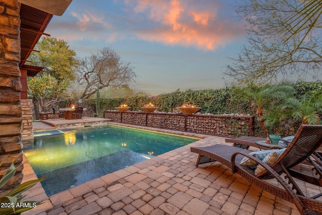 pool at dusk featuring a patio area