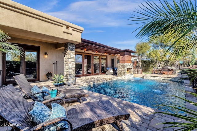 view of pool with pool water feature, an outdoor stone fireplace, and a patio area