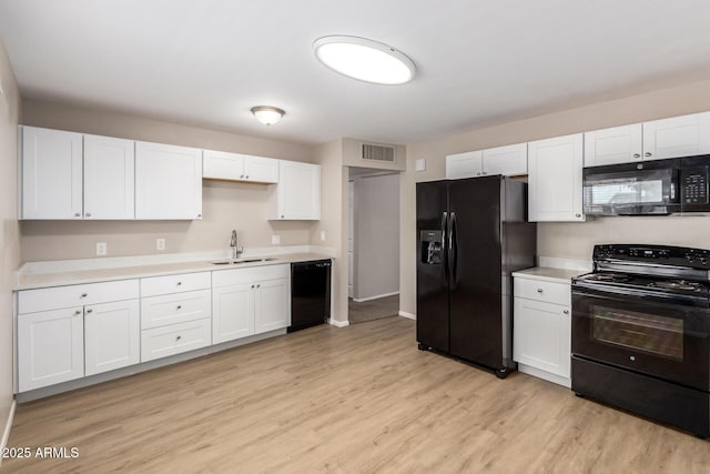 3118 W Aster Dr, Phoenix, AZ 85029 - kitchen featuring black appliances, white cabinets, light wood-style flooring, and light countertops