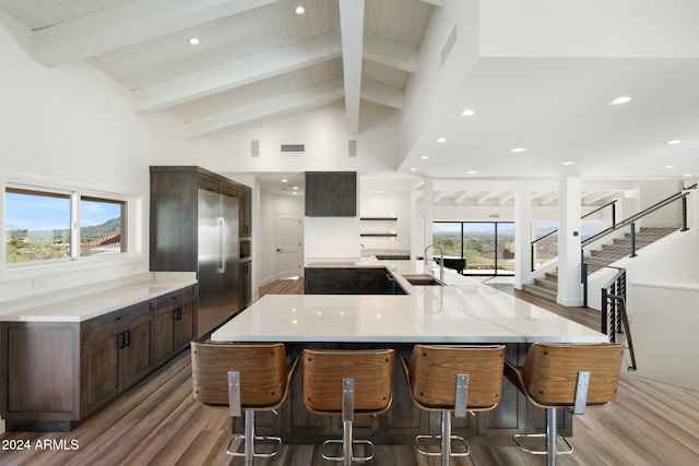 kitchen with hardwood / wood-style floors, a breakfast bar, high vaulted ceiling, sink, and beamed ceiling