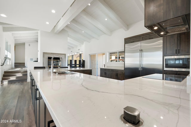 kitchen featuring light stone counters, a premium fireplace, beamed ceiling, high vaulted ceiling, and built in appliances