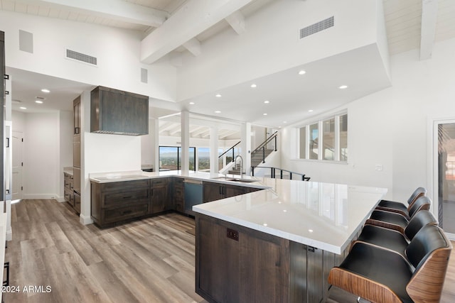 kitchen featuring dishwasher, light wood-type flooring, dark brown cabinets, kitchen peninsula, and a breakfast bar area