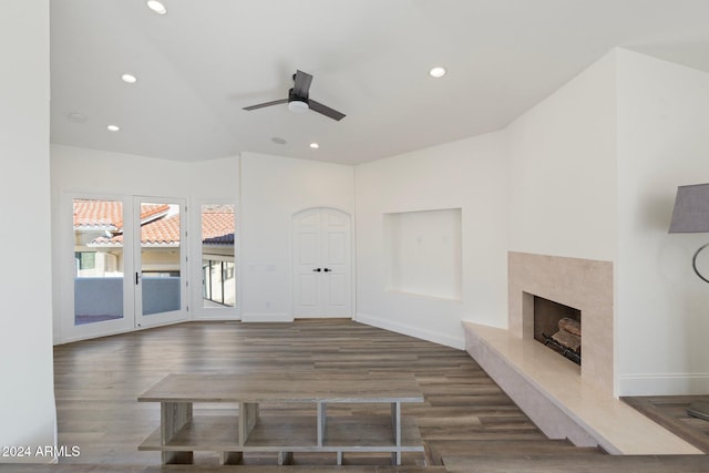 unfurnished living room featuring ceiling fan, a high end fireplace, and dark wood-type flooring