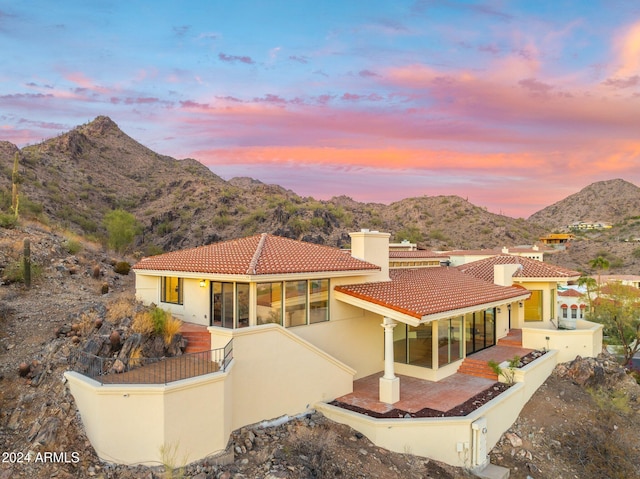 back house at dusk featuring a patio area and a mountain view