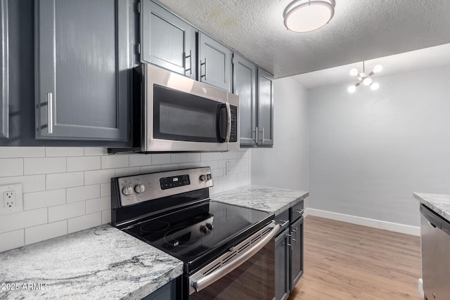 kitchen with gray cabinets, light stone countertops, appliances with stainless steel finishes, and light hardwood / wood-style floors