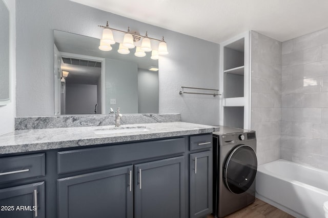 bathroom with washer / clothes dryer, vanity, hardwood / wood-style flooring, and tiled shower / bath