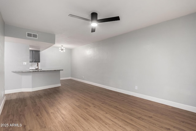 unfurnished living room featuring dark hardwood / wood-style flooring, sink, and ceiling fan with notable chandelier