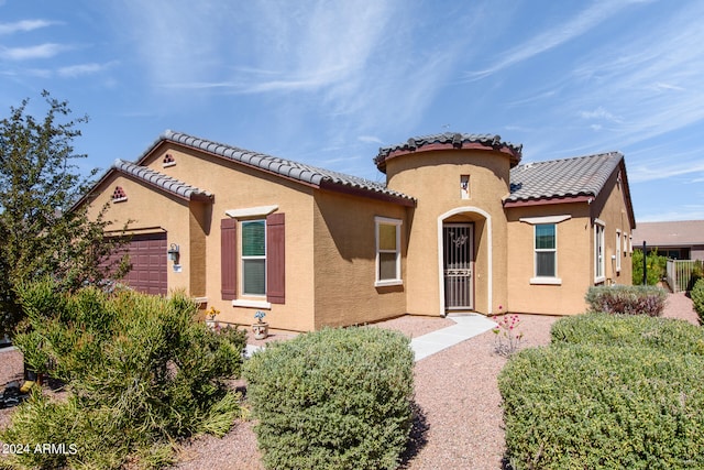 mediterranean / spanish-style home featuring a garage, a tile roof, and stucco siding