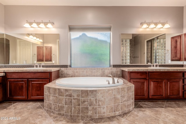 bathroom featuring tile patterned flooring, tiled bath, and vanity